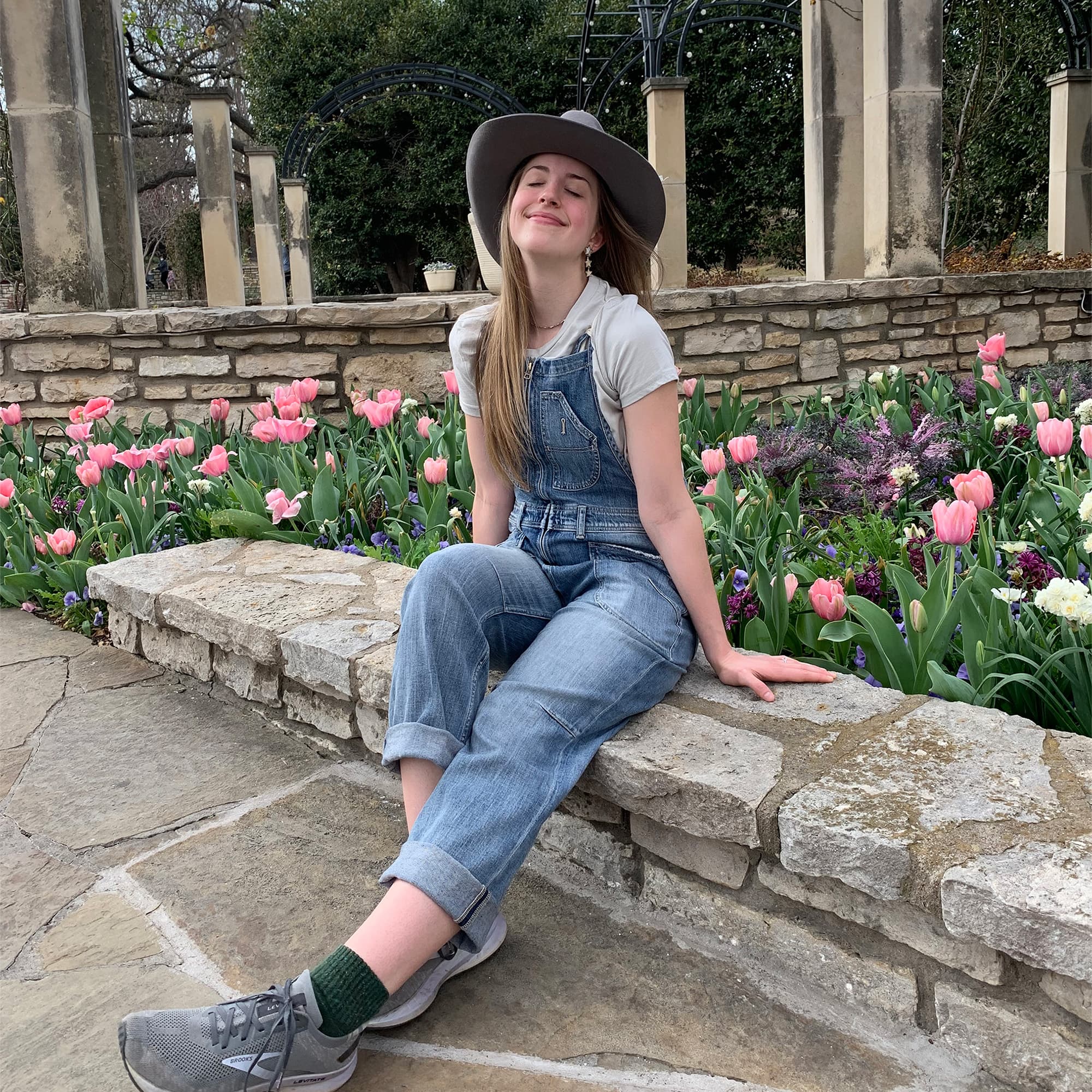 Indigo in a cowgirl hat, sitting in a garden